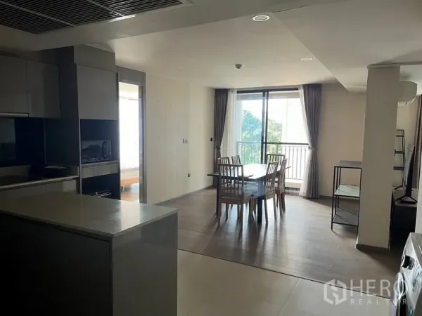 公寓 出租在Pathum Wan, Bangkok - 开放式厨房与餐区，中岛操作台，大窗与阳台可见绿意。