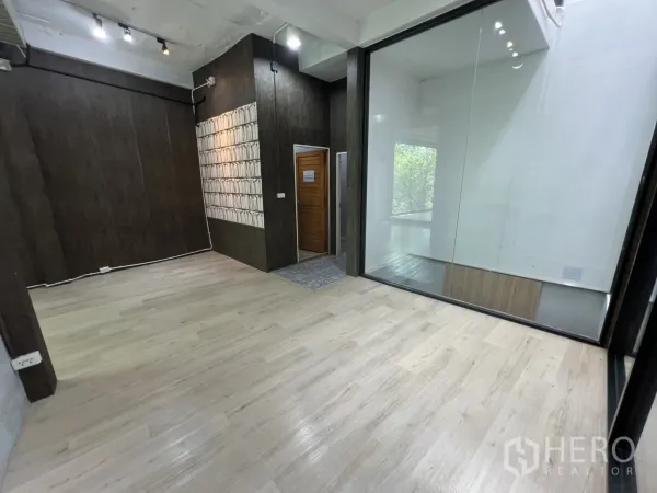 零售空间 出租在Watthana, Bangkok - 分区零售区，深色木饰面与大型室内玻璃隔断。