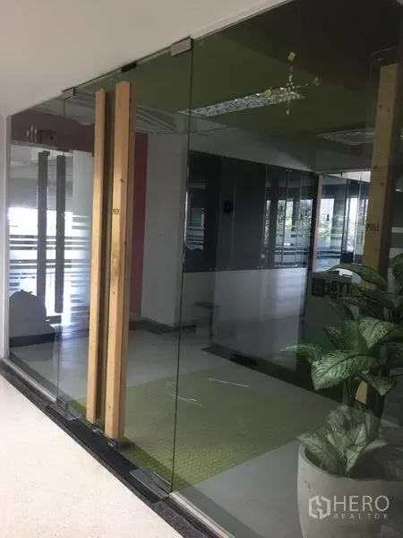 สำนักงาน ให้เช่าในBang Kapi, Bangkok - ทางเข้าออฟฟิศประตูกระจกเต็มบาน มือจับไม้ พร้อมกระถางต้นไม้ ที่บางกะปิ