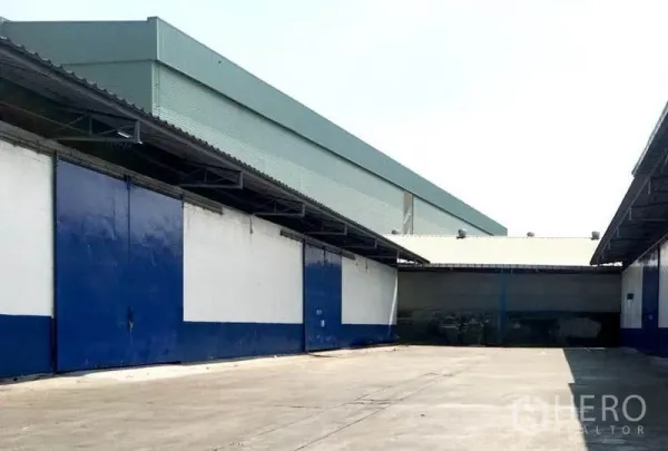 คลังสินค้า ให้เช่าในBang Phli, Samut Prakan - ลานกลางแจ้งระหว่างอาคารโกดัง ประตูสีน้ำเงินขนาดใหญ่ มีชายคาคลุมท่าโหลดและพื้นที่กลับรถบรรทุกกว้าง