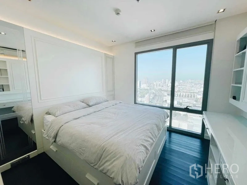 Condominium for rent or sale in Bang Kho Laem, Bangkok - Bedroom with large window, built-in desk and shelves, and sweeping city views.
