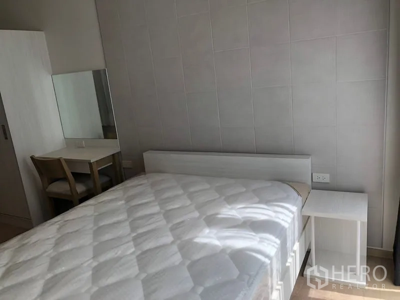 Condominium for rent in Watthana, Bangkok - Bright bedroom with white bed, side table and a dressing desk against a tiled feature wall.