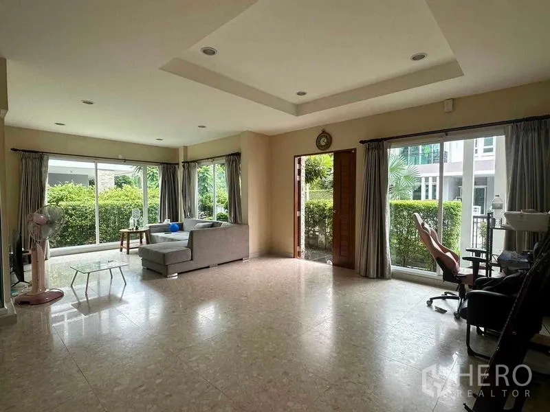 Detached House for sale in Saphan Sung, Bangkok - Open-plan living room with sofa, big windows and garden views.
