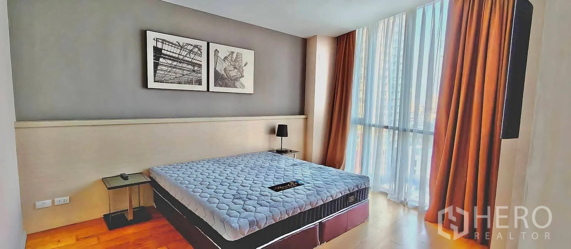 Condominium for rent in Watthana, Bangkok - Bedroom with large windows, wood flooring, bedside tables, and blackout curtains.