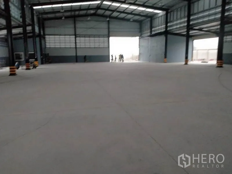 โรงงาน ให้เช่าหรือขายในPhanat Nikhom, Chon Buri - พื้นโรงงานกว้างมองออกสู่ประตูม้วนขนาดใหญ่ใต้หลังคาเมทัลชีท