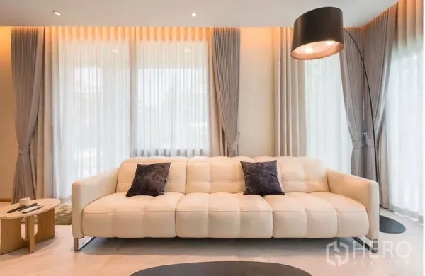 Detached House for rent or sale in Bang Kapi, Bangkok - Bright living room with large windows, sheer curtains and a cream sofa.
