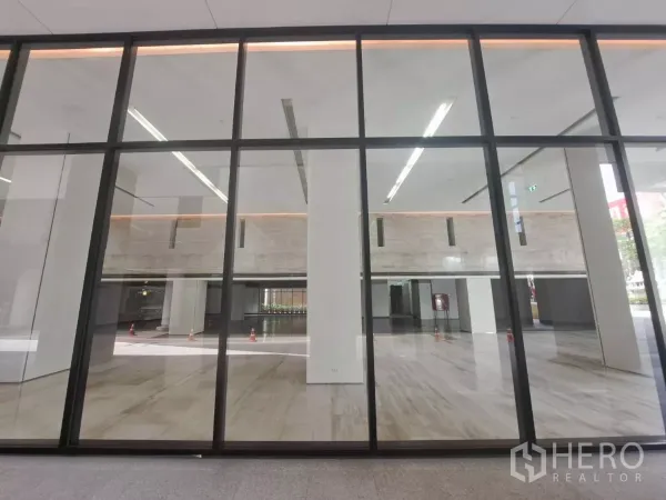 零售空间 出租 - 大面积玻璃店面与双层挑高室内，抛光石材地面明亮通透。