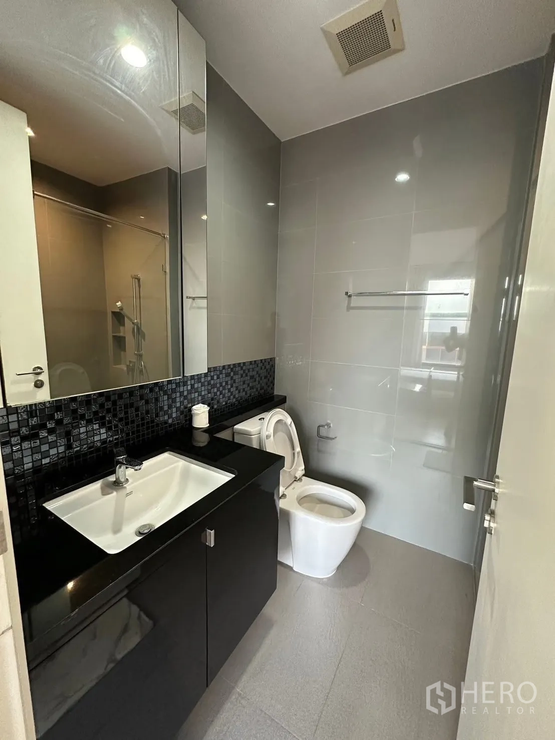 คอนโด for rent or sale in Chatuchak, Bangkok - ห้องน้ำที่สองพร้อมกระจกบานใหญ่ เคาน์เตอร์สีดำ และโถสุขภัณฑ์