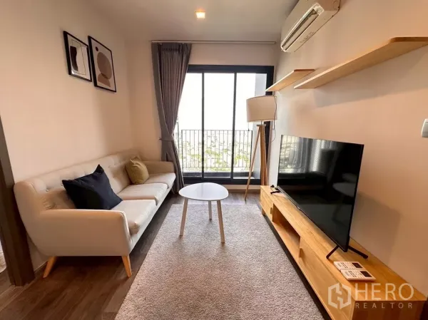 Condominium for rent in Chatuchak, Bangkok - Living area facing sliding glass doors with city view and wall shelves.