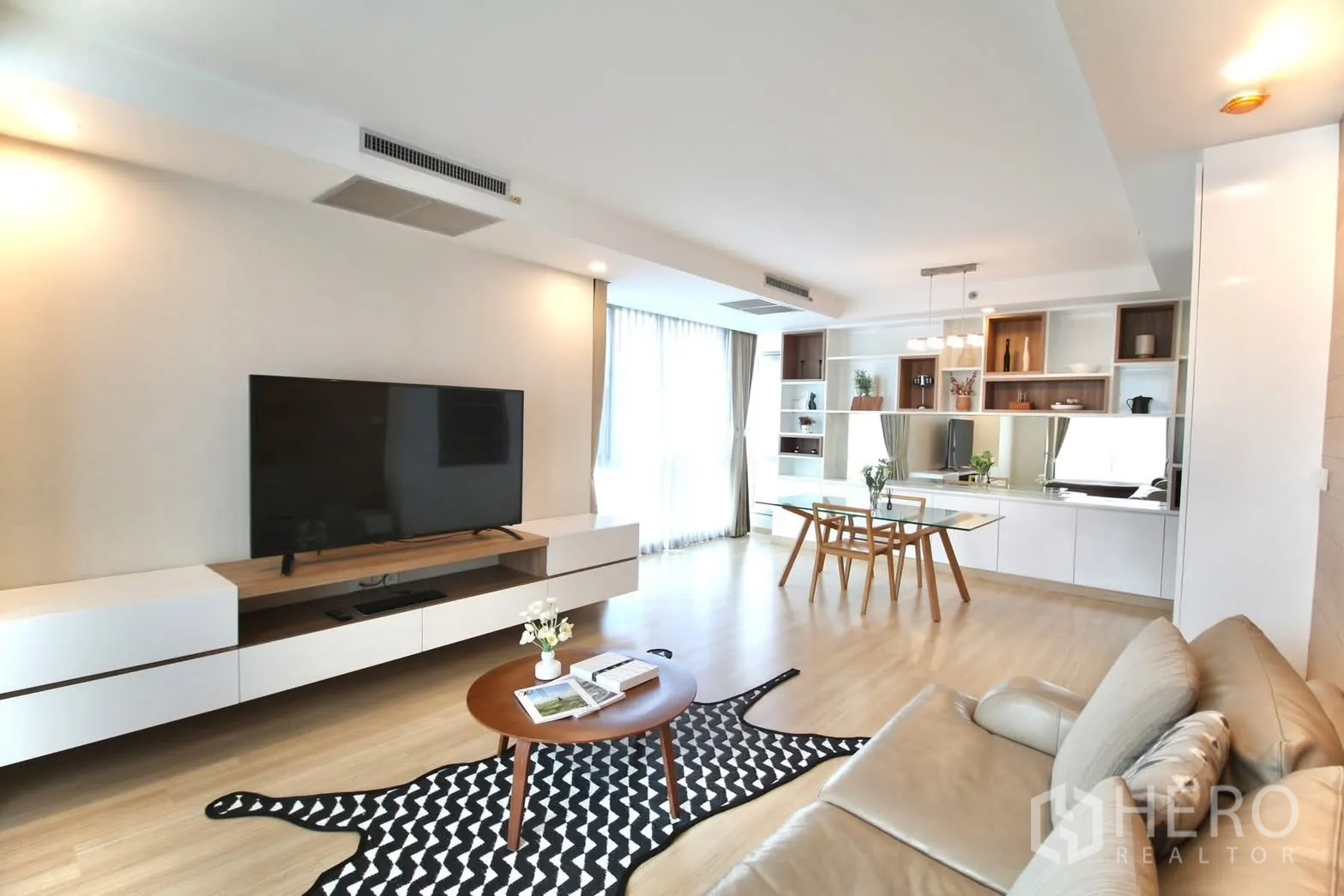 คอนโด for rent in Pathum Wan, Bangkok - ห้องนั่งเล่นกว้างพร้อมชั้นวางทีวี ตู้บิลท์อิน โต๊ะอาหารกระจก และพรมลาย