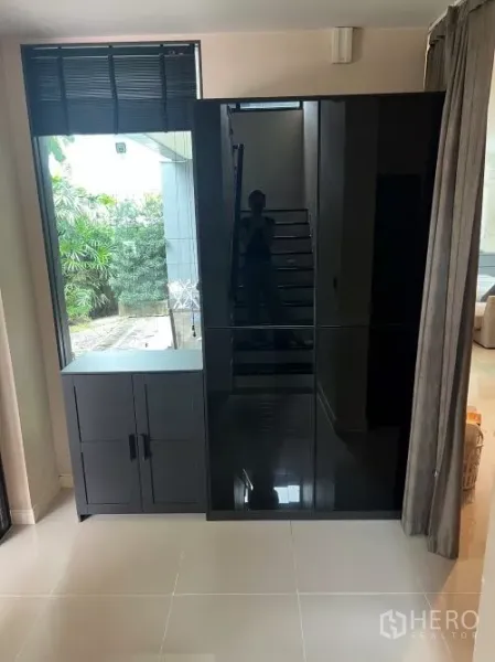 独立式住宅 出租在Bang Kapi, Bangkok - 入户角落的黑色亮面衣柜，旁有窗户与楼梯。