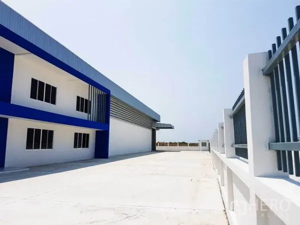 Warehouse for rent in Samut Prakan - Long driveway beside the warehouse with secure metal fencing and ample truck maneuvering space.