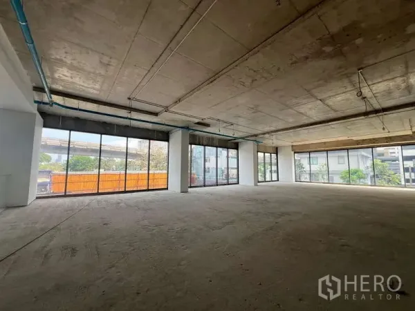 零售空间 出租 - 毛坯零售空间，落地玻璃与开放式布局，外露混凝土天花，可见街景。