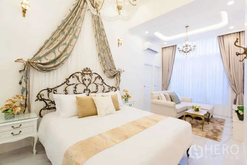 Townhouse for rent in Lat Phrao, Bangkok - Stylish bedroom with draped canopy headboard, sofa sitting area and high ceiling.
