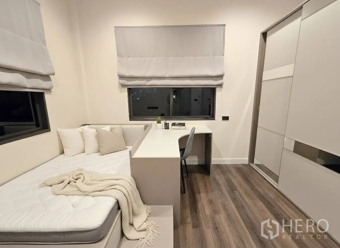 บ้าน for rent or sale in Bang Phli, Samut Prakan - ห้องนอนพร้อมเตียงเดย์เบด โต๊ะทำงานมุมห้อง และหน้าต่างคู่พร้อมมู่ลี่