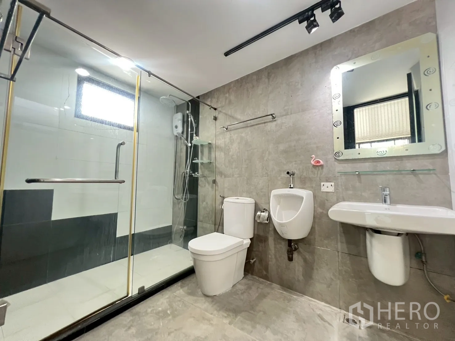 Detached House for rent or sale in Wang Thonglang, Bangkok - Modern bathroom featuring glass shower enclosure, toilet, urinal and vanity.