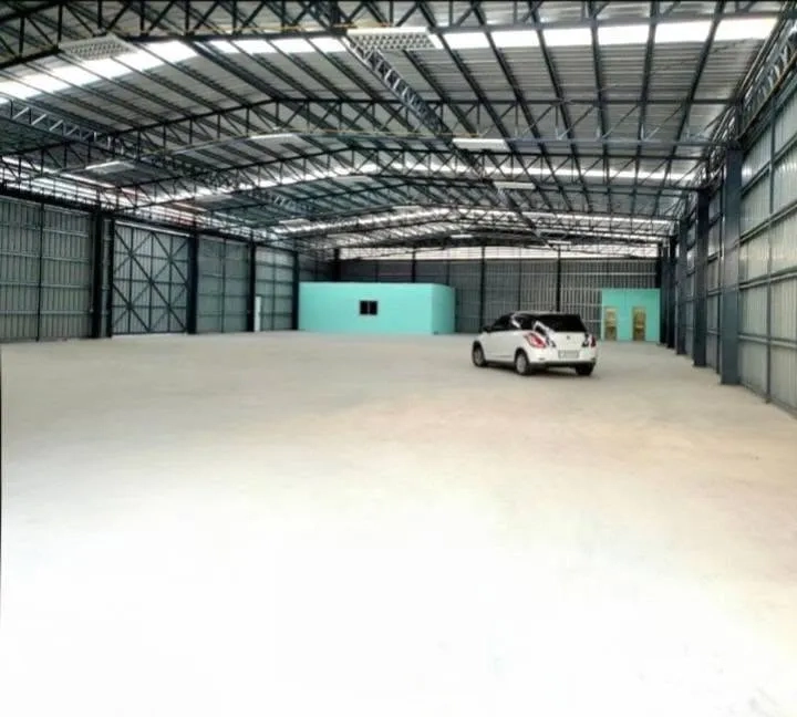 Warehouse for rent in Phaya Thai, Bangkok - Spacious warehouse interior with a high steel truss roof, concrete floor, and small internal rooms.