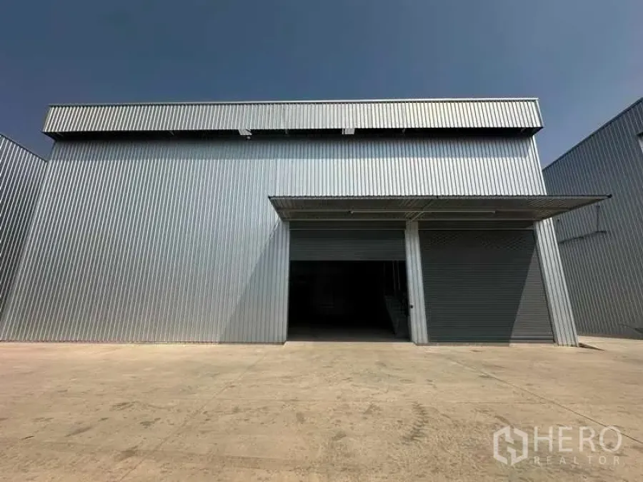 工厂 出租在Wang Noi, Phra Nakhon Si Ayutthaya - 金属板外立面的工厂，双卷帘门，前方有带雨棚的宽阔装卸坪。