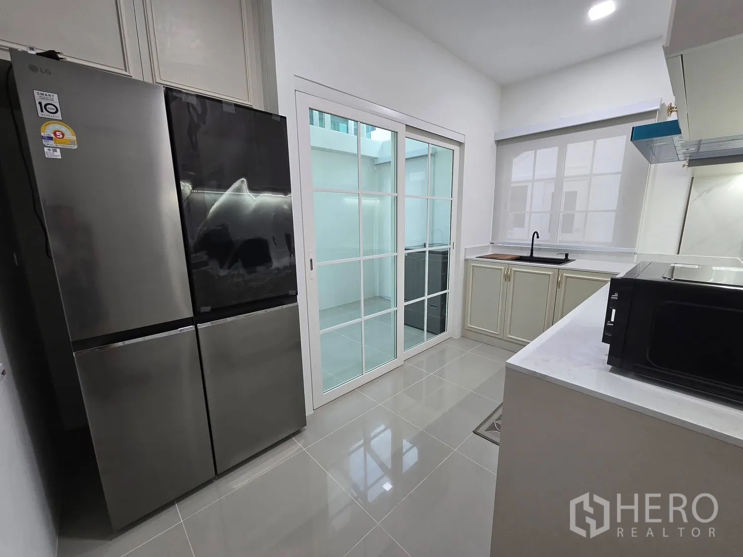บ้านแฝด for rent in Mueang Samut Prakan, Samut Prakan - ครัวปิดมีประตูกระจกบานเลื่อน ตู้เย็นสแตนเลสขนาดใหญ่ และท็อปขาว