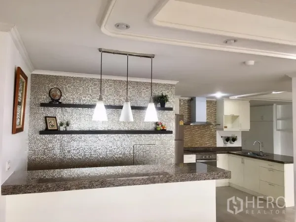 公寓 出售在Watthana, Bangkok - 带吊灯的吧台、悬浮搁架与质感墙面，旁为L形石材台面厨房