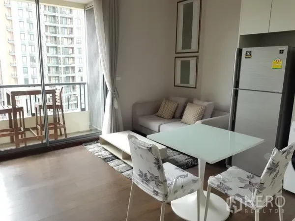 公寓 出租在Ratchathewi, Bangkok - 开放式客餐厅，沙发与玻璃餐桌连接通往可观景的阳台。