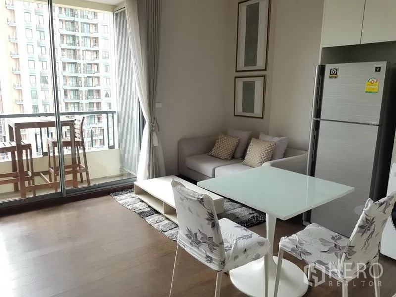 公寓 出租在Ratchathewi, Bangkok - 开放式客餐厅，沙发与玻璃餐桌连接通往可观景的阳台。