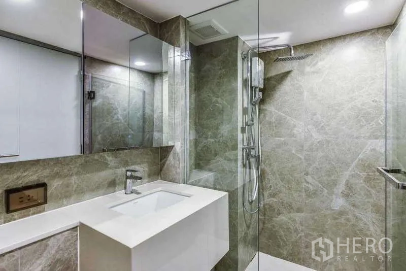 Condominium for rent in Huai Khwang, Bangkok - Bathroom featuring glass-enclosed rain shower and long vanity.