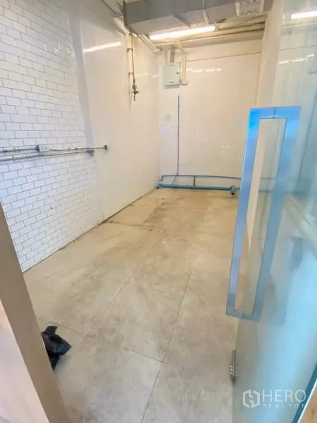 พื้นที่ขายปลีก ให้เช่าในWatthana, Bangkok - มุมมองจากประตูกระจกเข้าสู่พื้นที่ร้าน พื้นกระเบื้องสีเบจและท่อสาธารณูปโภค.