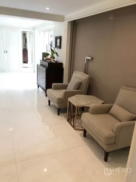 Shophouse for rent or sale in Chatuchak, Bangkok - Hallway lounge with two armchairs, side table and glossy white tile floor.