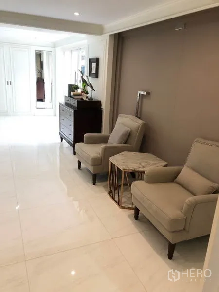 Shophouse for rent or sale in Chatuchak, Bangkok - Hallway lounge with two armchairs, side table and glossy white tile floor.
