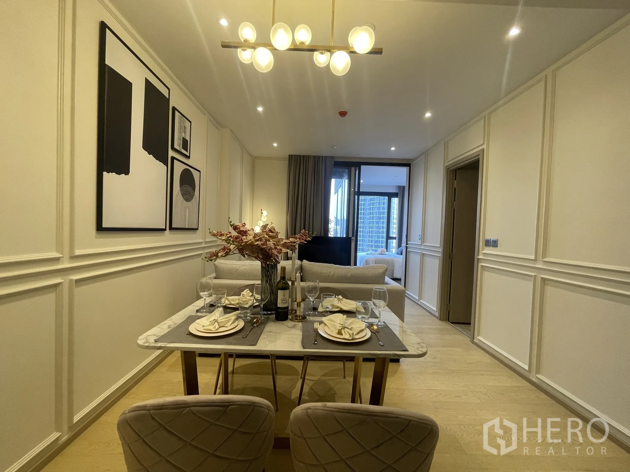 คอนโด ให้เช่าในDin Daeng, Bangkok - มุมมองจากโซนรับประทานอาหารไปยังห้องนั่งเล่นและห้องนอน พร้อมงานศิลปะและแสงไฟอบอุ่น