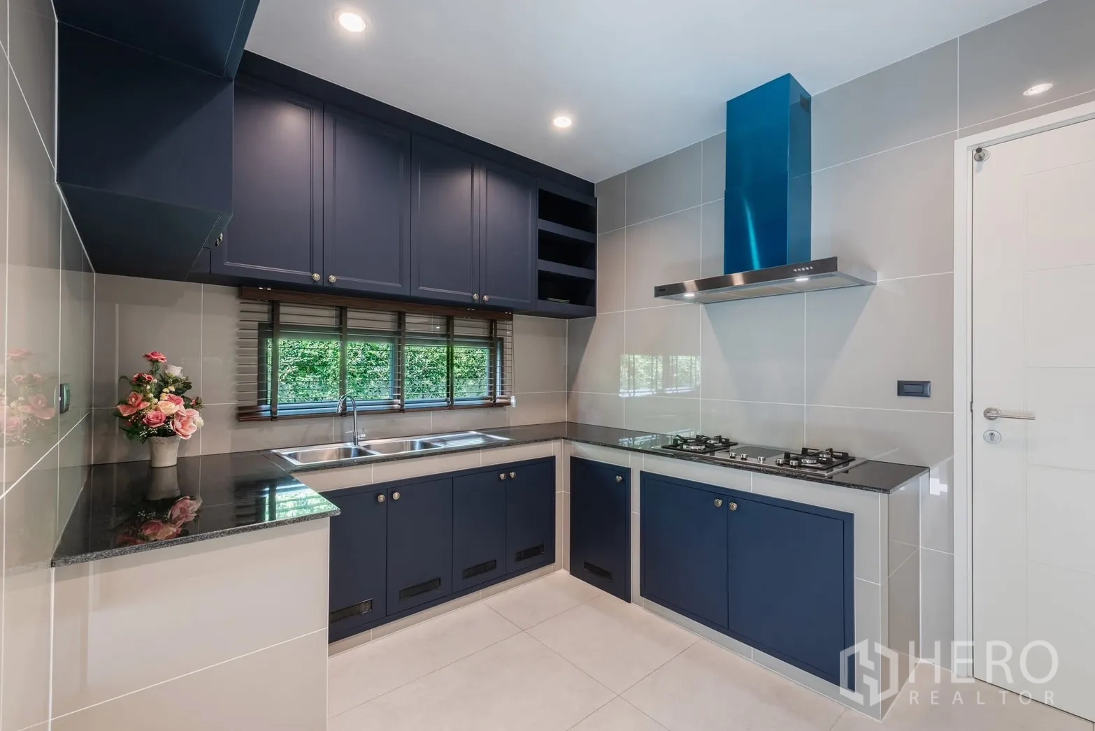 Detached House for rent or sale in Bang Phli, Samut Prakan - Modern U-shaped kitchen with blue cabinetry, gas cooktop, and stainless sink.