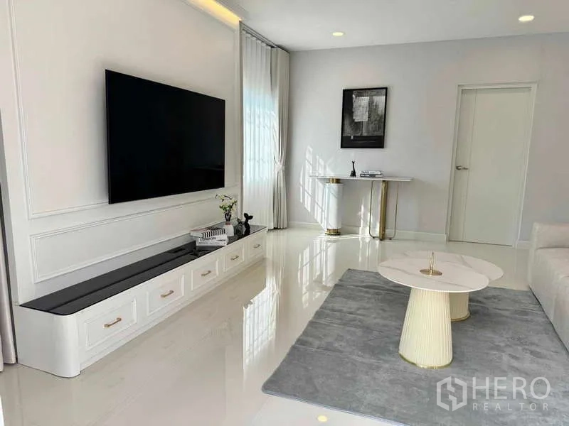 Detached House for rent or sale in Bang Phli, Samut Prakan - Modern lounge with wall-mounted TV, glossy floors, round coffee tables and a sleek console.