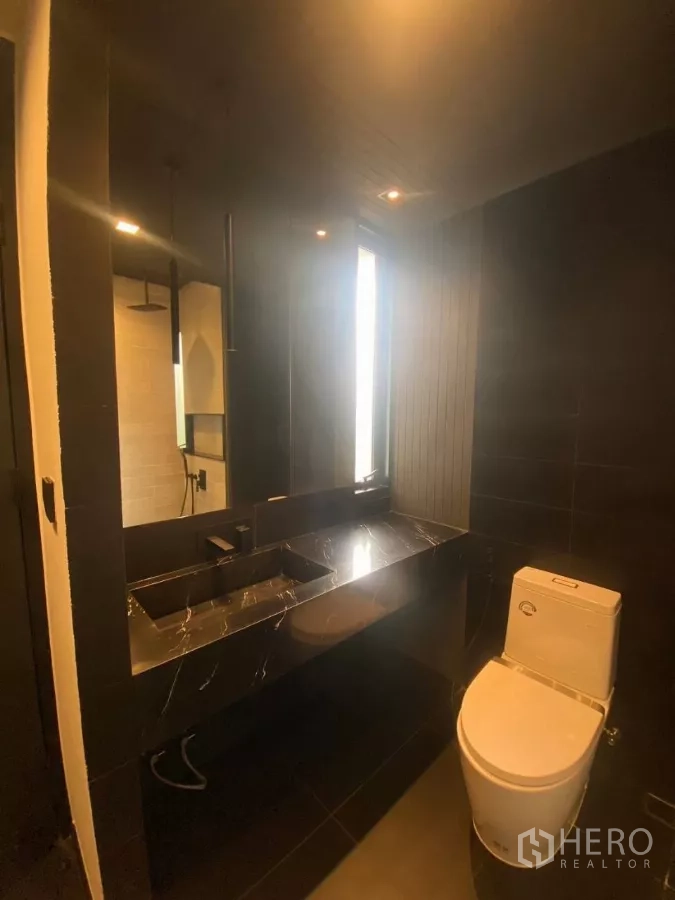 ทาวน์เฮาส์ ให้เช่าในHuai Khwang, Bangkok - ห้องน้ำแขกเคาน์เตอร์หินอ่อนสีดำและโถสุขภัณฑ์ทันสมัย.