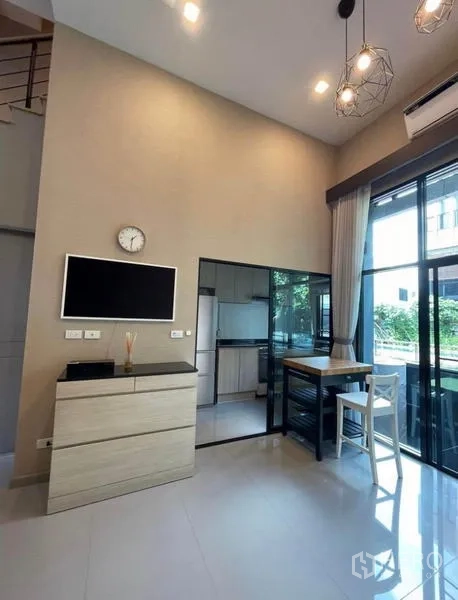 Townhouse for rent in Yan Nawa, Bangkok - Dining corner with TV console and sliding glass doors opening to a patio garden.