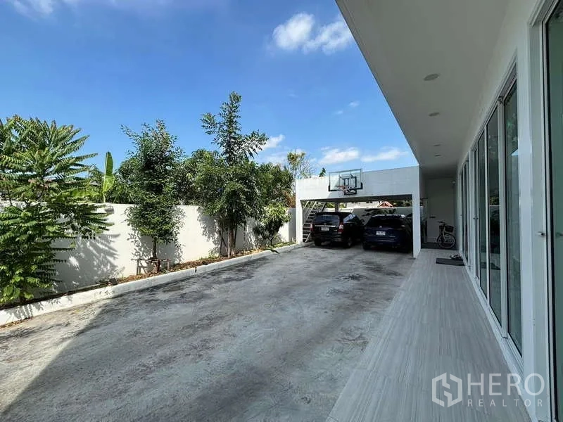 บ้าน ให้เช่าในLat Krabang, Bangkok - ทางรถเข้าพร้อมโรงจอดรถมีหลังคา แป้นบาส และต้นไม้ริมกำแพง