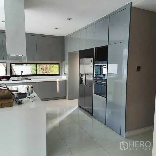 独立式住宅 出租或出售在Mueang Nonthaburi, Nonthaburi - 现代灰色厨房，带岛台、嵌入式烤箱和对开门冰箱。