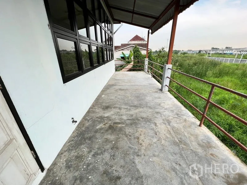Warehouse for rent in Min Buri, Bangkok - Outdoor balcony terrace with railing overlooking greenery beside the warehouse.