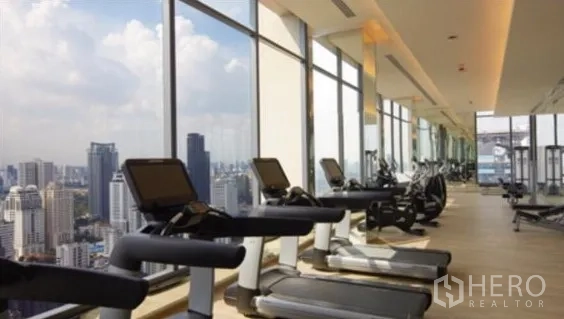 Condominium for rent in Watthana, Bangkok - Fitness center with treadmills lined along windows overlooking the Bangkok skyline.