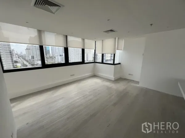 Office Space for rent in Khlong Toei, Bangkok - Corner workspace with wraparound windows, city views, recessed lighting and light wood flooring.