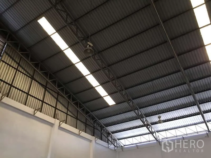 Factory for rent in Bang Bo, Samut Prakan - Corrugated metal roof showing long strip lighting and hanging industrial fans.