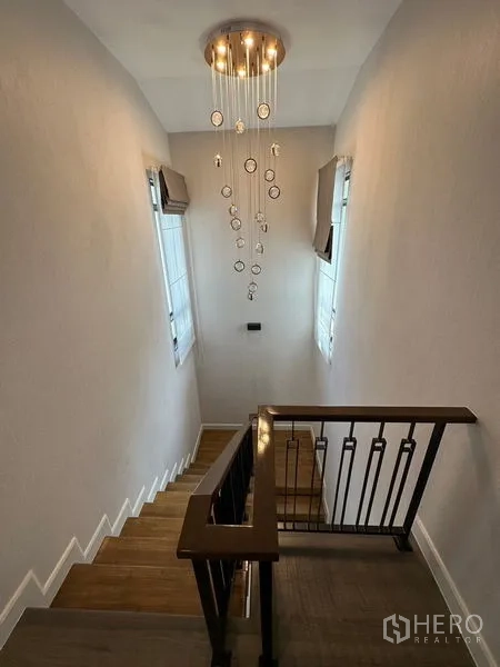 Detached House for rent or sale - Staircase with wood steps, metal balustrade and cascading chandelier.