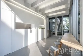 零售空间 出租在Khlong Toei, Bangkok - 极简白色空间，弧形灯带与高挑梁顶，玻璃入口