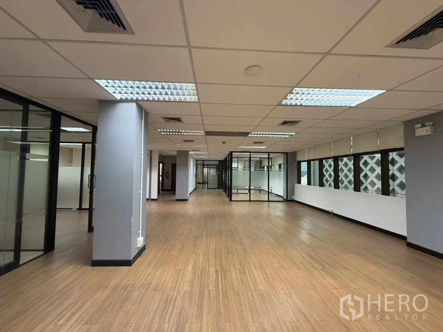 办公空间 出租 - 长形开放式办公区，日光灯、立柱与玻璃会议室。