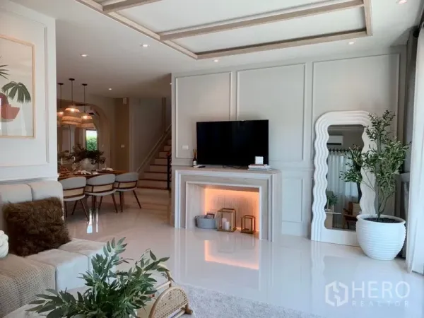 Detached House for sale - Light-filled living and dining zone with TV feature wall, large mirror, potted plants and recessed lighting.