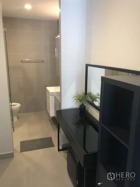 Condominium for rent or sale in Pathum Wan, Bangkok - Hallway leading to a gray-tiled bathroom with vanity and a glass shower enclosure.