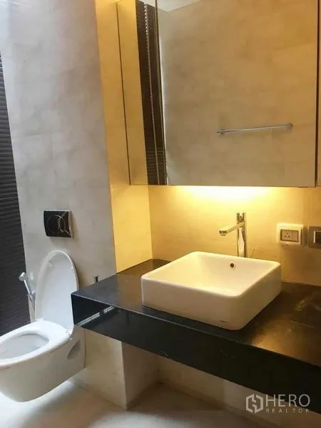 Condominium for rent in Bang Rak, Bangkok - Contemporary bathroom with square countertop basin and backlit mirror.
