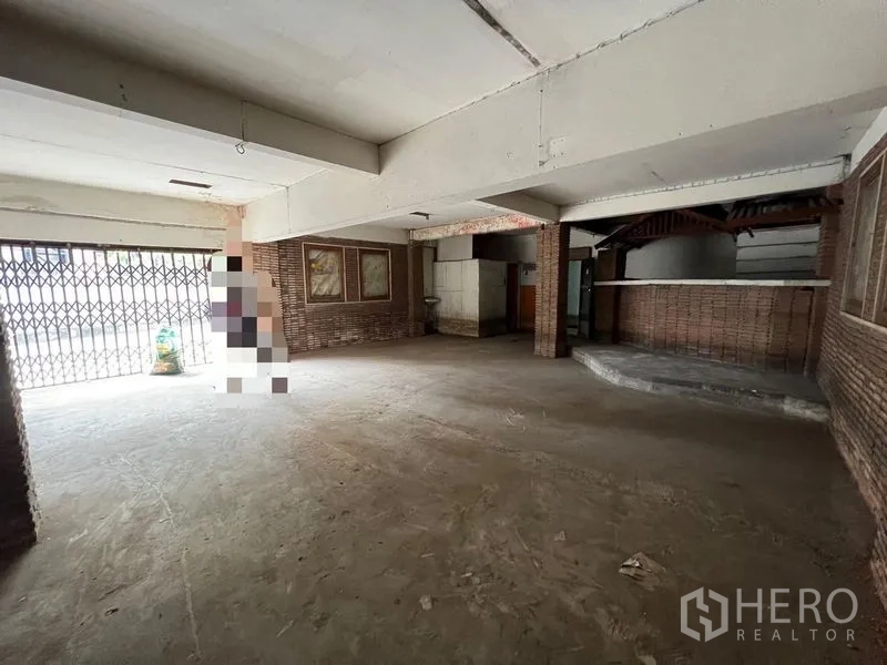 Shophouse for rent or sale in Bang Khen, Bangkok - Open commercial space on the ground floor with folding gate entrance and counter area.