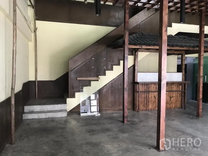 零售空间 出租在Khlong Toei, Bangkok - 室内木质楼梯与内置吧台，外露梁架与混凝土地面，适合零售用途