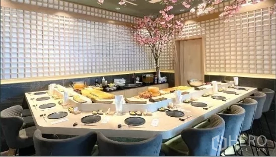 零售空间 出租 - 日式餐厅内U形寿司吧台与座位，格纹墙面与樱花装饰